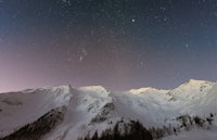 a mountain covered in snow with stars above it
