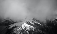a black and white photo of a mountain covered in clouds