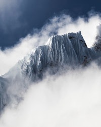 a mountain covered in clouds under a blue sky