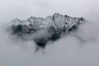 a mountain covered in clouds with a cloudy sky