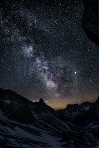 the milky in the night sky above a snowy mountain