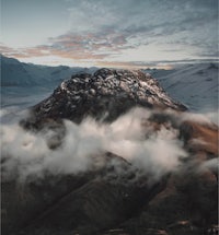 a mountain covered in clouds at sunrise